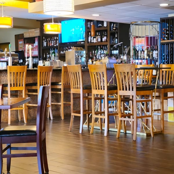 Interior view of Yenat Guada Ethiopian Cuisine bar area with wooden stools and liquor bottles.