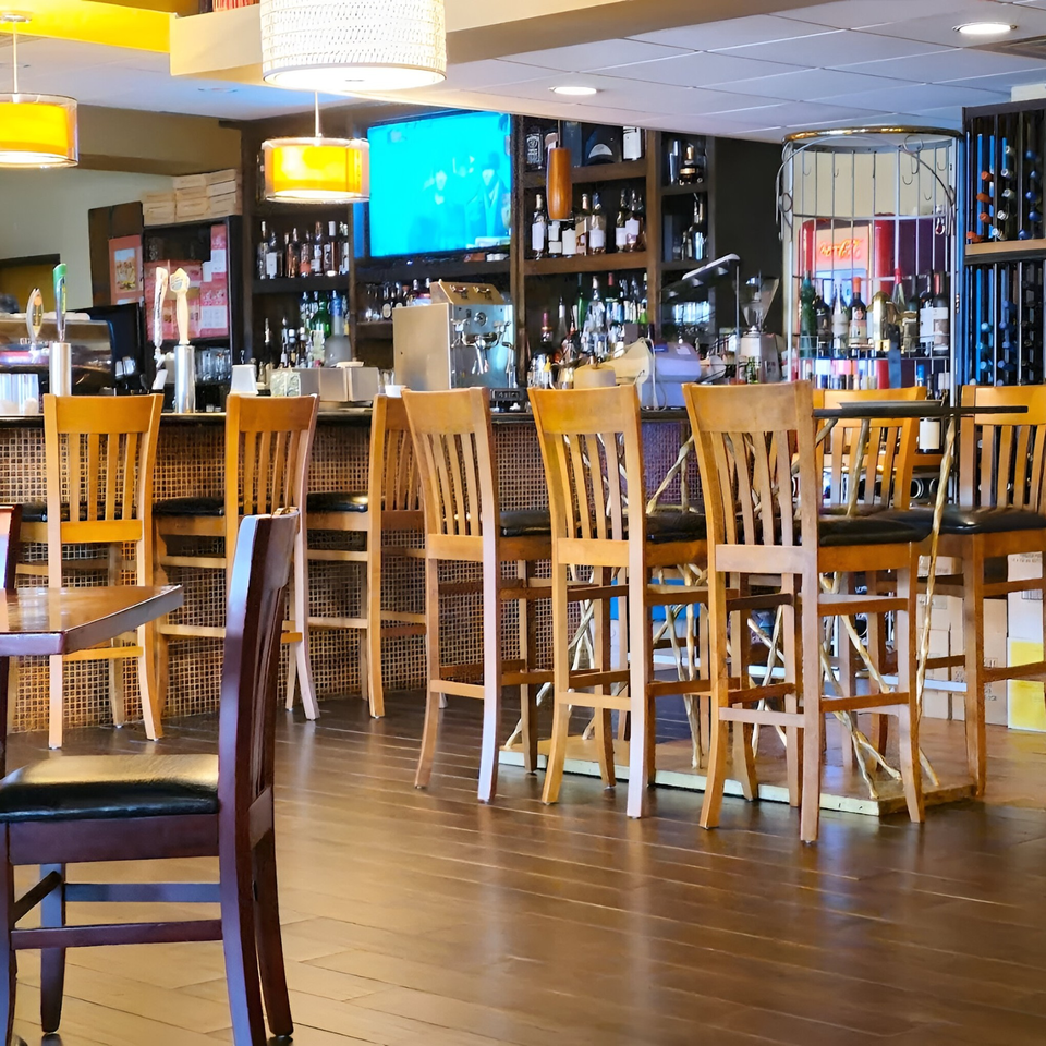 Interior view of Yenat Guada Ethiopian Cuisine bar area with wooden stools and liquor bottles.