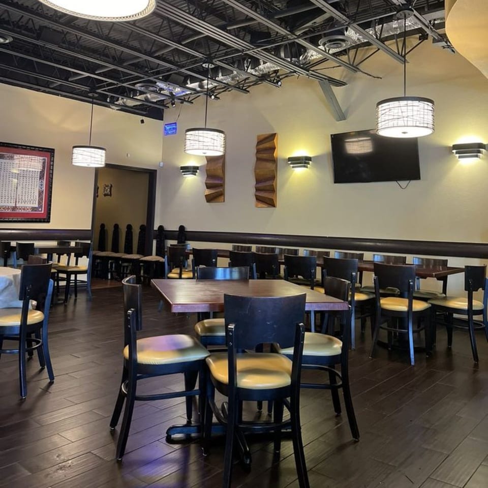 Empty dining room at Yenat Guada Ethiopian Cuisine with dark tables, chairs, and exposed ceiling.