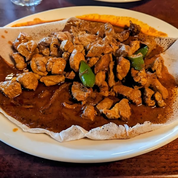 Ethiopian Tibs, a dish of cubed meat and green peppers in a rich sauce, served on injera.